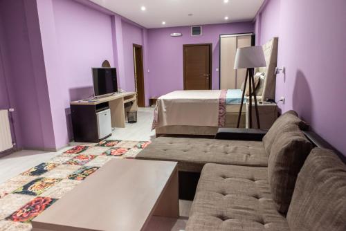 1 dormitorio con paredes moradas, 1 cama y 1 sofá en Hotel Gold, en Pljevlja
