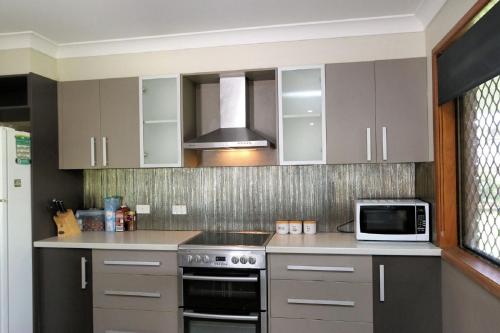 a kitchen with a stove and a microwave at 12 Wilfred Street in Bargara