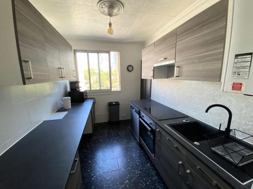 - une cuisine avec des comptoirs noirs et un évier dans l'établissement Résidence Rouviere - Grand appartement Vue Mer Budget Maitrisé MAE-9664, à Marseille