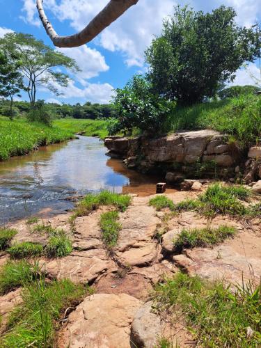 a river with rocks and trees on the side at Casa colonial a metros del arroyo Piribebuy in Piribebuy