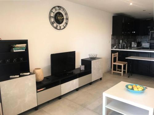 un salon avec une cuisine dotée d'une horloge murale dans l'établissement Résidence Luberon - Charmant appartement dans un domaine arboré au bord du lac MAE-7044, à Six-Fours-les-Plages