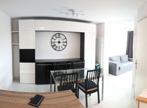 - un salon avec une horloge, une table et des chaises dans l'établissement Résidence Pinedes Aryana - Joli appartement climatisé dans domaine avec piscine MAE-5614, à Six-Fours-les-Plages