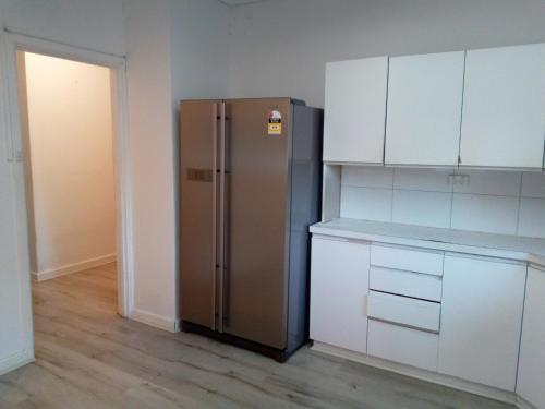a kitchen with a stainless steel refrigerator and white cabinets at Homestay upon Kenwick Station in Perth