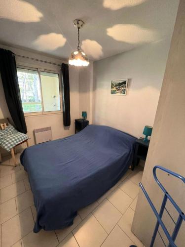 une chambre avec un lit avec un couvre-lit bleu dans l'établissement Résidence Palmiers - Appartement 6 couchages dans un domaine arboré MAE-2854, à Six-Fours-les-Plages