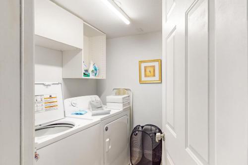 a white bathroom with a sink and a washing machine at Historic Gillespie Getaway in Sarasota