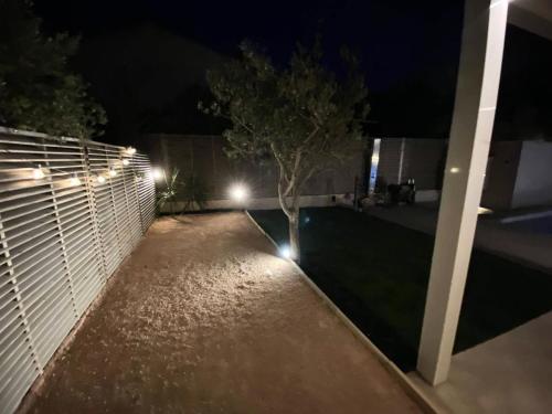 een achtertuin 's nachts met een hek en een boom bij Résidence La Batisde - Maisons & Villas pour 8 Personnes 314 in Six-Fours-les-Plages