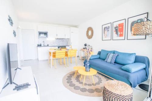 un salon avec un canapé bleu et une table dans l'établissement SUNLIGHT HORIZON -Terrasse vue mer - Accès direct plage- Parking - Idéal Famille TOPPROSCONCIERGERIE, à La Grande Motte