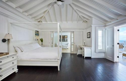 a white bedroom with a white bed and a desk at Sugar Beach, A Viceroy Resort in Soufrière