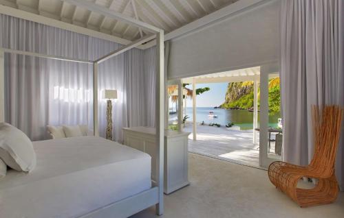 a bedroom with a bed and a view of the ocean at Sugar Beach, A Viceroy Resort in Soufrière