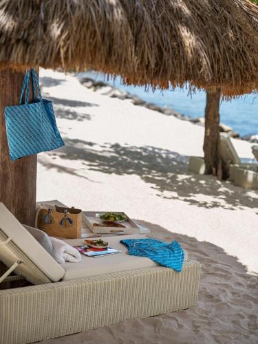 a beach with a straw umbrella and a table with food at Sugar Beach, A Viceroy Resort in Soufrière