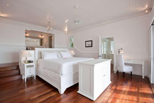 a white bedroom with a white bed and a desk at Sugar Beach, A Viceroy Resort in Soufrière