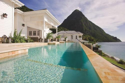 a swimming pool in front of a house with a mountain at Sugar Beach, A Viceroy Resort in Soufrière