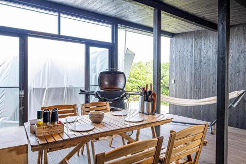 Un comedor con mesa y sillas y ventanas. en THE GLAMPING PLAZA 伊勢志摩BASE, en Ugata