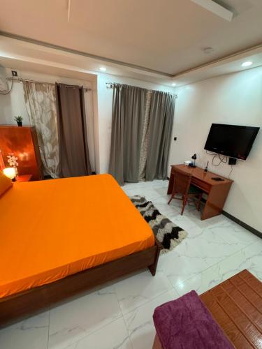 a bedroom with an orange bed and a desk at Dal Ak jamm in Guediawaye