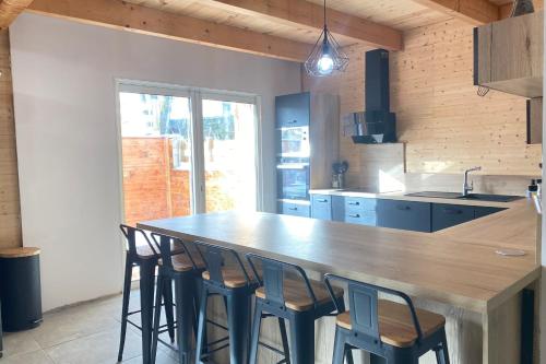 a kitchen with a large wooden counter with stools at Lovely duplex with cinema room in Le Dévoluy