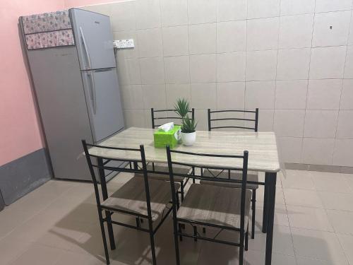 a table with chairs and a refrigerator in a room at Raudah Homestay in Kota Bharu