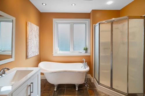 bagno con vasca, doccia e lavandino di *NEW* Stunning Waterfront Bright Chalet with Spa a Saint-Calixte