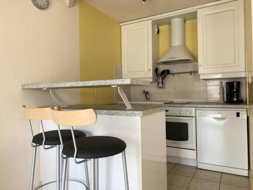 une cuisine avec des placards blancs et deux tabourets de bar dans l'établissement Résidence Les Bains - Charmant duplex à 50m de la promenade du Val André. MAE-6594, à Pléneuf-Val-André