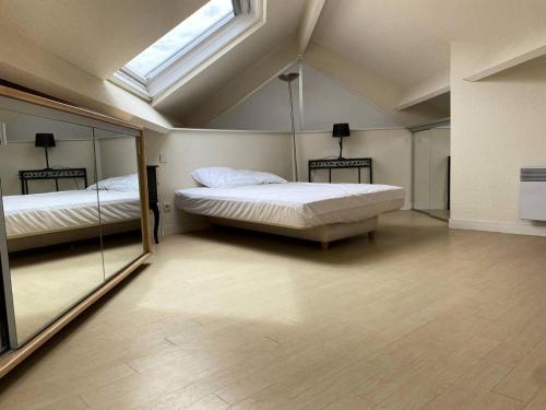 Cette grande chambre comprend deux lits et une lucarne. dans l'établissement Résidence Les Bains - Charmant duplex à 50m de la promenade du Val André. MAE-6594, à Pléneuf-Val-André