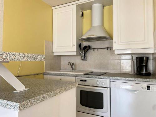 une cuisine avec des armoires blanches et un four à plaques de cuisson dans l'établissement Résidence Les Bains - Charmant duplex à 50m de la promenade du Val André. MAE-6594, à Pléneuf-Val-André