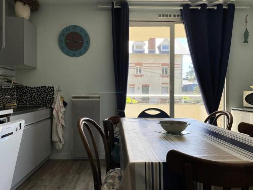 une cuisine avec une table et une horloge au mur dans l'établissement Résidence Parc - Appartement T3 , dans une résidence à 100m de la plage, au cœur du Val André. MAE-6714, à Pléneuf-Val-André