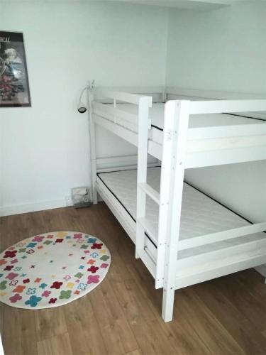 Ce lit superposé blanc se trouve dans un dortoir doté d'un tapis. dans l'établissement Résidence Amiraute - Appartement de 50m², refait à neuf, dans une résidence à deux pas des plages. MAE-6724, à Pléneuf-Val-André