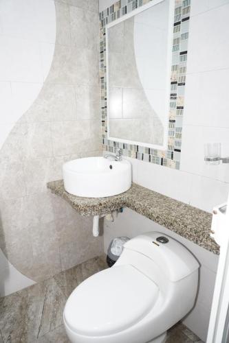 a bathroom with a white toilet and a sink at Hotel SMIR in Huaquillas