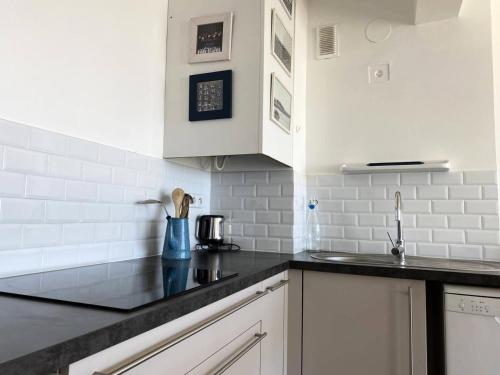 une cuisine avec des armoires blanches et un comptoir noir dans l'établissement Résidence Casino - Studio pour 2 Personnes 484, à Pléneuf-Val-André