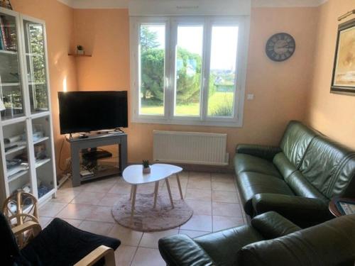 - un salon avec un canapé en cuir vert et une télévision dans l'établissement Résidence 620-pleneuf Val Andre - Belle maison néo-bretonne dans un quartier résidentiel sur les hauteurs du Val André MAE-7614, à Pléneuf-Val-André
