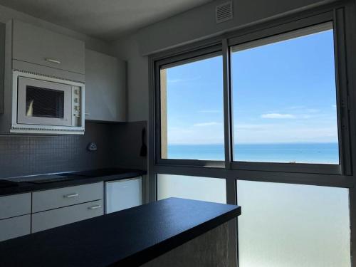 une cuisine avec une grande fenêtre et un four micro-ondes dans l'établissement Résidence Dauphins - Appartement T2 en centre bourg du Val-André. MAE-6524, à Pléneuf-Val-André