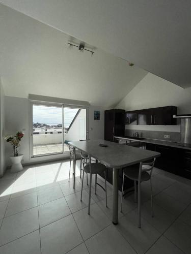 une cuisine avec une table et des chaises et une fenêtre dans l'établissement Résidence Le Rocher - Appartement duplex avec vue sur les toits du val andré MAE-5384, à Pléneuf-Val-André