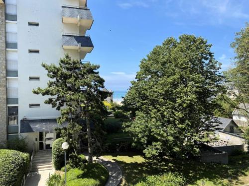 un immeuble avec deux arbres devant lui dans l'établissement Résidence Parc - Appartement T2 de 42m², à deux pas de la plage du Val André. MAE-6564, à Pléneuf-Val-André