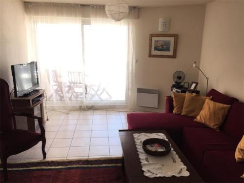 un salon avec un canapé rouge et une télévision dans l'établissement Résidence Les Bains - Charmant T3 à deux pas de la plage du Val André. MAE-6644, à Pléneuf-Val-André