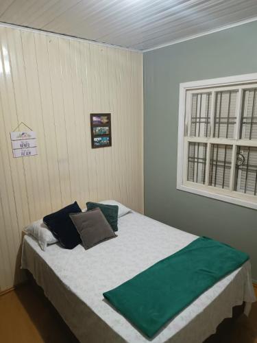 a bedroom with a bed with green pillows and a window at Casarão das Figueiras in Caxias do Sul