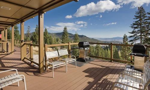 a deck with two benches and a grill and mountains at Worldmark Lake Tahoe in Stateline