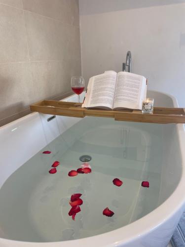 a bath tub with a book and a glass of wine at Alojamiento de invitados in Sauzal