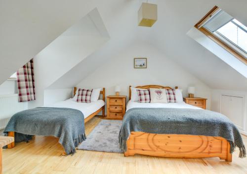 a attic bedroom with two beds and a window at The Old Post Room in Salhouse