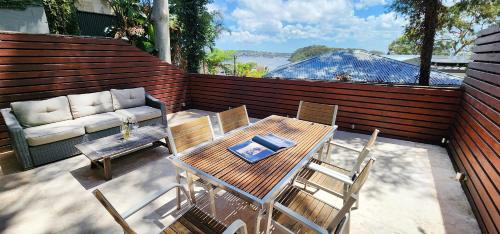 a patio with a table and chairs and a couch at Harbourside Escape: Sunlit Outdoor Terrace & Views in Sydney