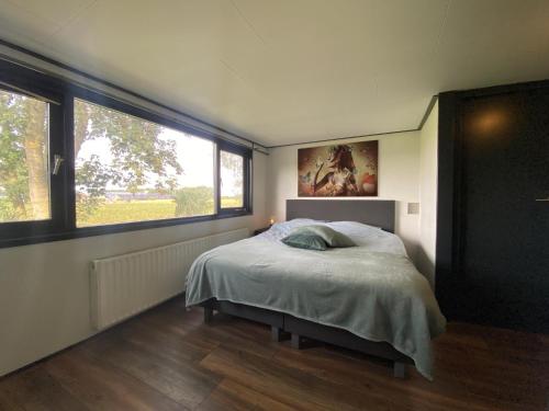 um quarto com uma cama e uma grande janela em De Kolibrie em Garderen