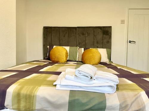 a bed with yellow pillows and white towels on it at 2 bedrooms haven near NEC, Airport in Curdworth