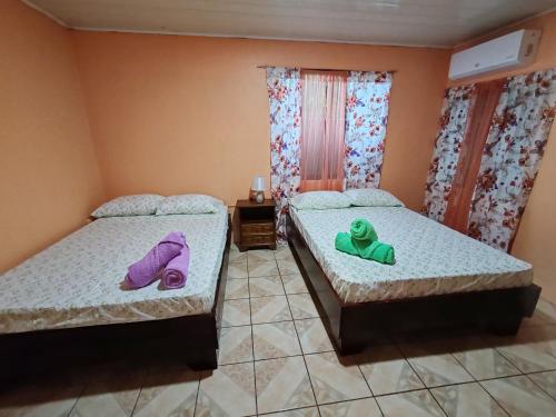 2 camas en una habitación con toallas moradas y verdes en Apartamento El Atardecer, en Puerto Viejo