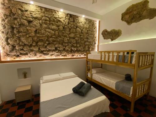 2 letti in una camera con parete in pietra di Casa Zaguan a Cartagena de Indias
