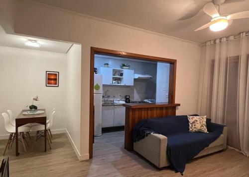 a bedroom with a bed and a table and a kitchen at Flat espaçoso e confortável no Piazza Navona in Porto Alegre