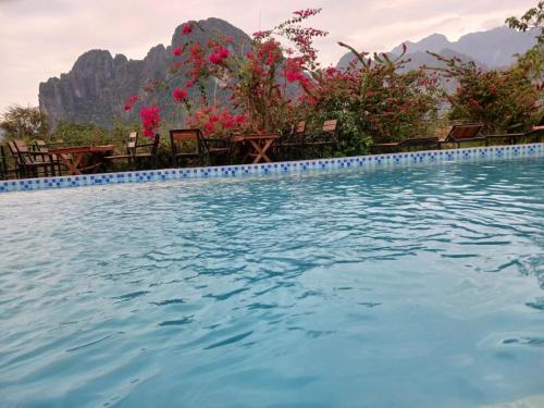uma piscina com cadeiras e montanhas ao fundo em Riverside Garden Hostel em Vang Vieng