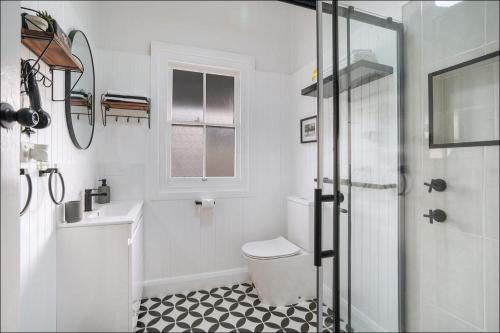 a white bathroom with a toilet and a sink at Lil's Cottage in Cessnock