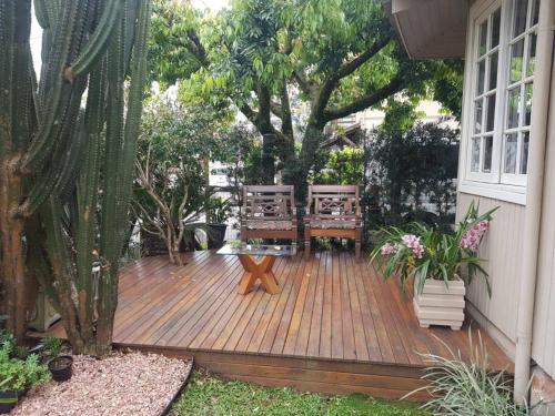 une terrasse en bois avec deux bancs et un arbre dans l'établissement Casa Mimosa, à Gramado