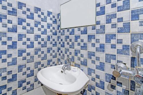 a bathroom with blue and white tiled walls and a sink at Hotel O Shibani & Suhani in Bhubaneshwar