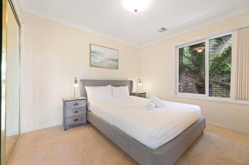 Un dormitorio con una cama grande y una ventana en Serene Mountain Haven with Scenic Balcony & Garden en Wentworth Falls