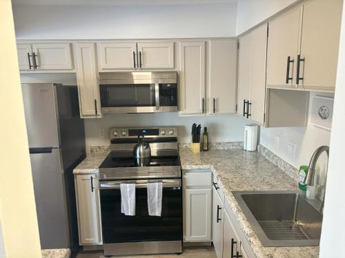a kitchen with white cabinets and a black stove top oven at Gorgeous Remodeled Classy Family Apartment in Granite City