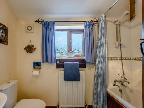 a bathroom with a toilet and a tub and a window at 2 bed in Tatterset 77765 in Tattersett